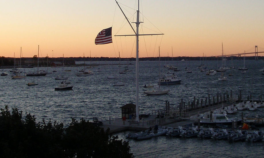 Billedet viser aften solen fra New York Yacht Clubs klubhus her i Newport. De fleste sejladser kommer til at foregå ude ved broen, som anes i baggrunden.