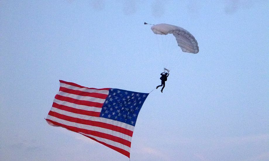Til lyden af en kvinde, der sang ”God Bless America” dalede det amerikanske flag fra en helikopter med en faldskærmsudspringer. Foto: Signe Storr