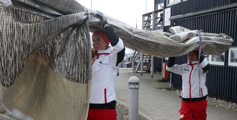 KDY-kvinder fra KDYs Farr 40 slæber på sejl. De er godt nok tunge, lød det fra kvinderne. Foto: Troels Lykke
