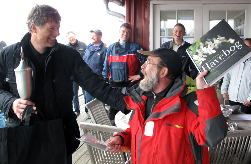 Jørgen Svendsen får havebog i præme af Lundeborg Sejlklubs stævneleder, der gav kommunesammenlægningen skylden for det regnfulde vejr. Foto: Troels Lykke