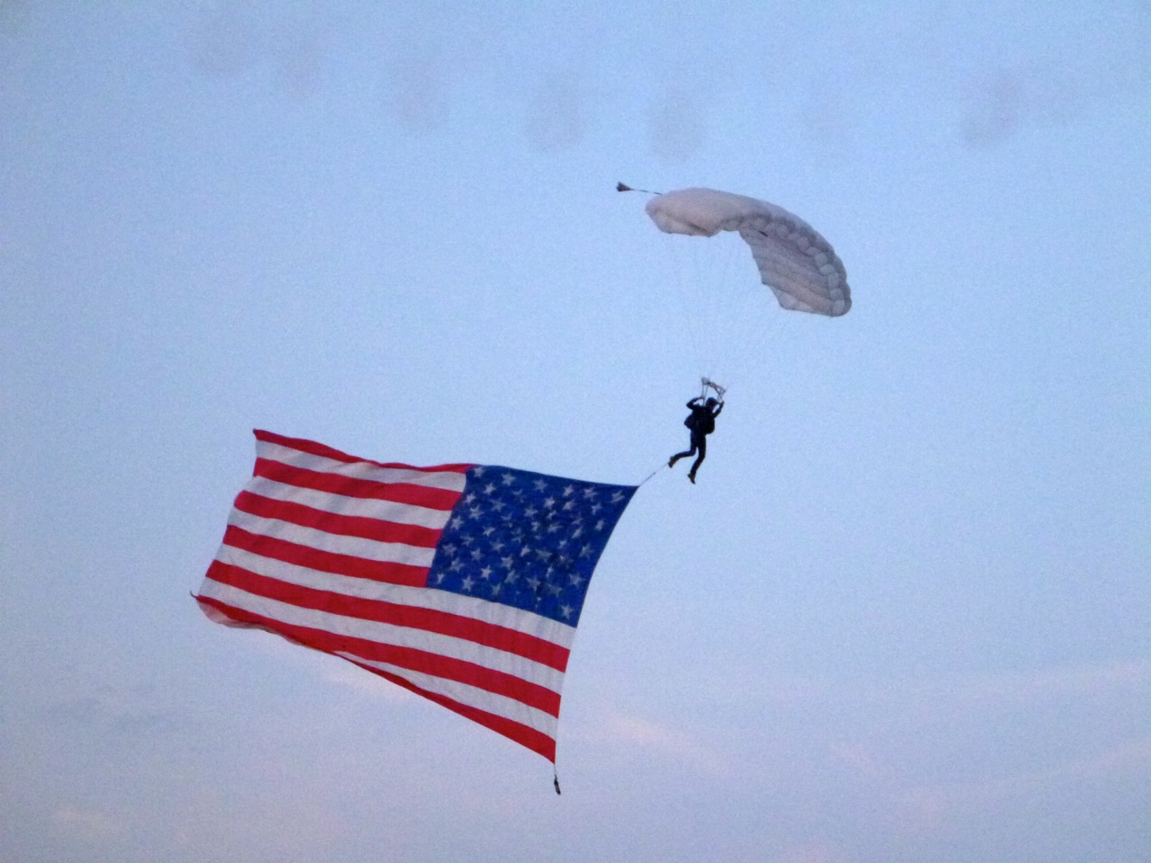 Til lyden af en kvinde, der sang ”God Bless America” dalede det amerikanske flag fra en helikopter med en faldskærmsudspringer. Foto: Signe Storr